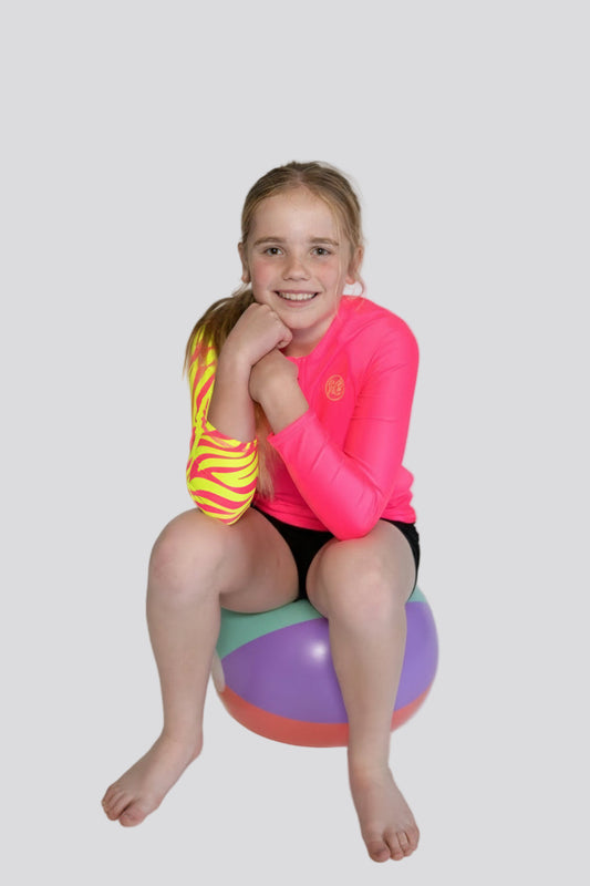 Child wearing bright Pink Sea Me Swimwear Zebra Rash Top.