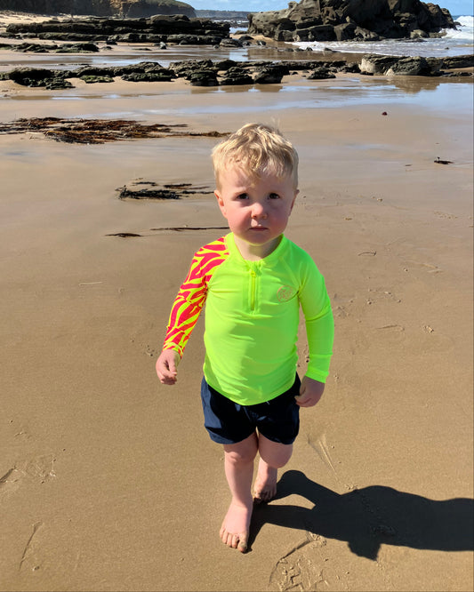 Child wearing bright Yellow Sea Me Swimwear Zebra Rash Top
at the beach.