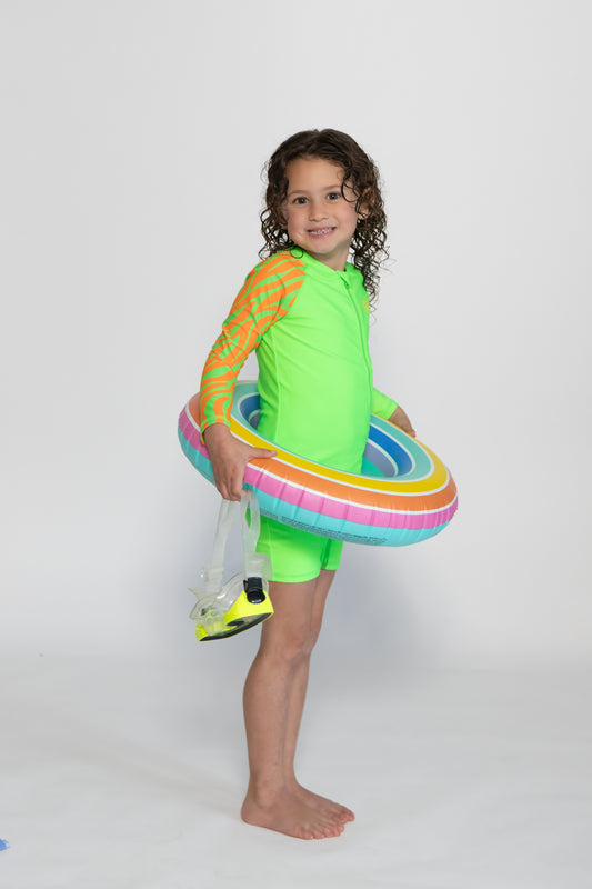 Child wearing bright Green Sea Me Swimwear Zebra Swimsuit
posing in front of White Background.