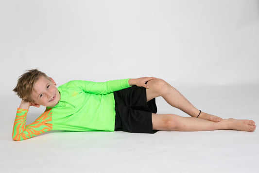 Child wearing bright Green Sea Me Swimwear Zebra Rash Top
posing for camera.