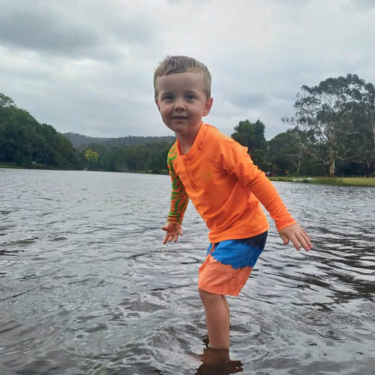 Child wearing bright Orange Sea Me Swimwear Zebra Rash Top
at the Lake.
